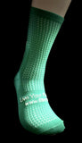 Green sock with textured pattern and text on a black background