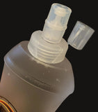 Clear spray nozzle on a black bottle against a dark background